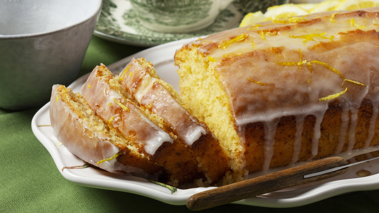 Aromatic lemon cake, covered with sugar icing and sprinkled with zest on an oblong white platter