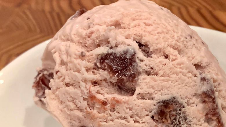 A scoop of roasted strawberry crème fraîche ice cream in a white bowl