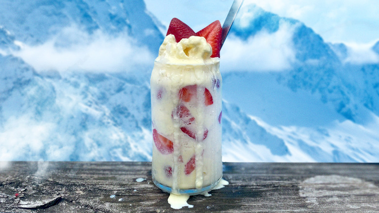 A strawberry snowball on a wooden table with mountains behind it