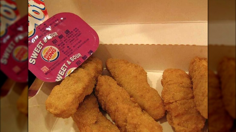 Close up of orginal chicken tenders from Burger King in takeout container with sweet and sour dipping sauce