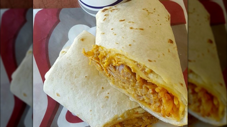 Close up of Taco Bell shredded chicken burrito in flour totrilla with queso cut in half