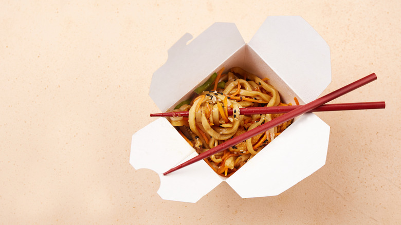 Noodles and chopsticks in a white Chinese takeout container