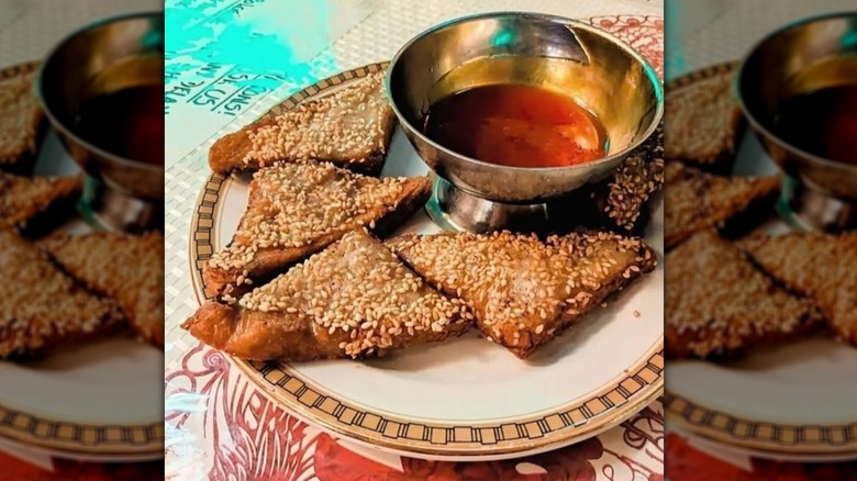 Sesame prawn toast on a platter with sauce