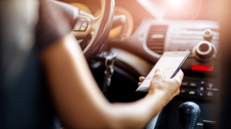 A woman holding a phone in her hand in the car