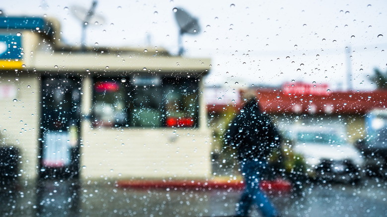 a rainy windshield looking out at a customer approaching a resturant