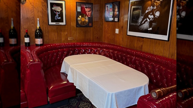 Red leather booth with Elvis memorabilia hanging on the walls, and white linen on table at Golden Steer