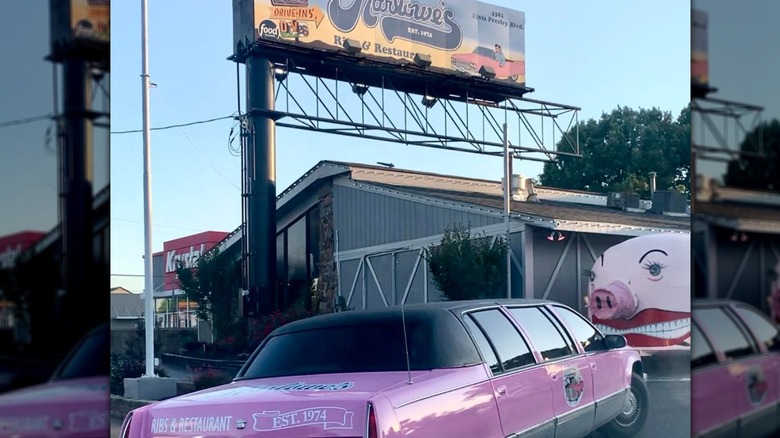 Pink Cadillac limo and Pig Bus parked outside of the entrace to Marlowe's, with Marlowe's billboard in background