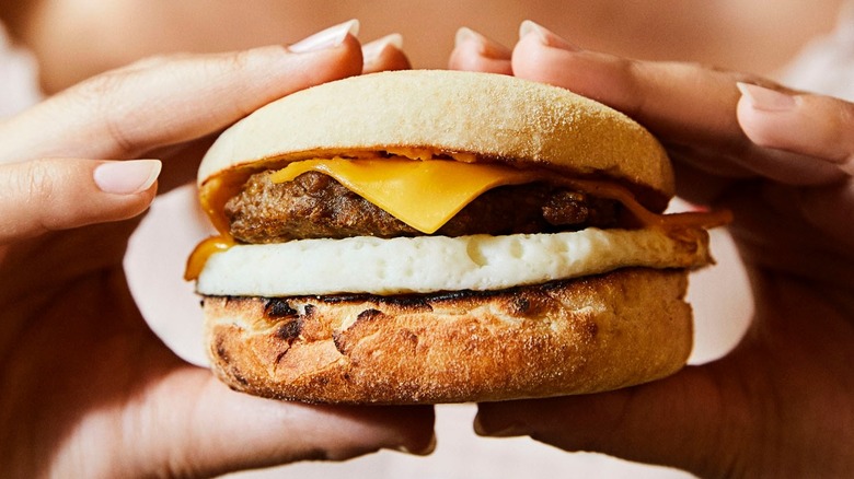 Hands holding a Dunkin' Donuts Beyond Sausage sandwich