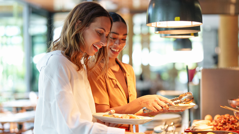 Two women serving themselves at a buffet