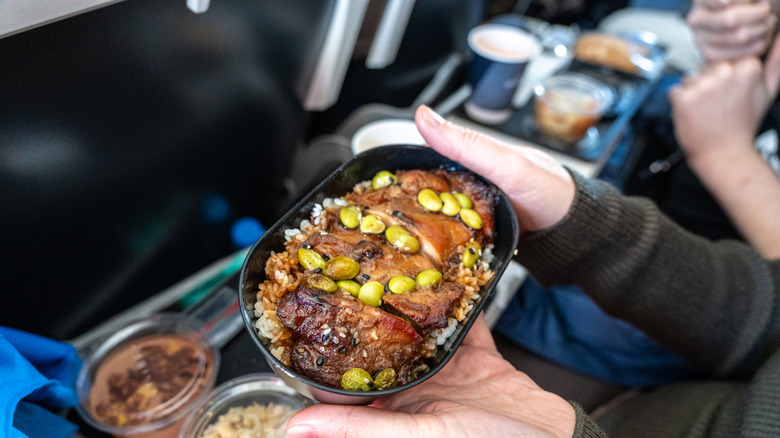 A passenger holding a tray of food on a flight