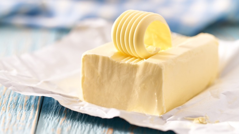 A stick of butter with a curled piece on the top