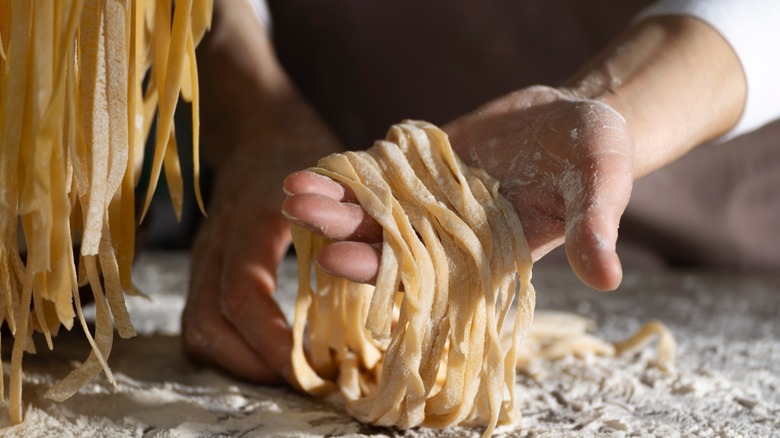 Hands holding raw handmade fettuccine noodles