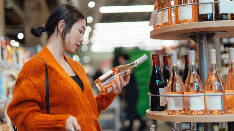 Woman looking at a bottle of wine in a store