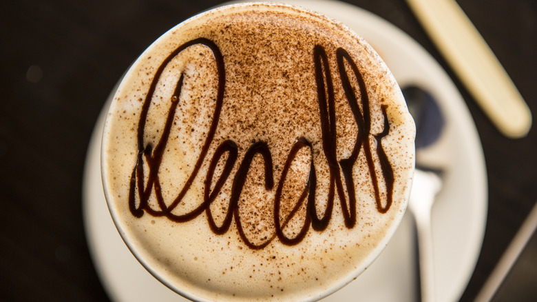 A cup of coffee with "Decaff" written in the foam with chocolate across the top.