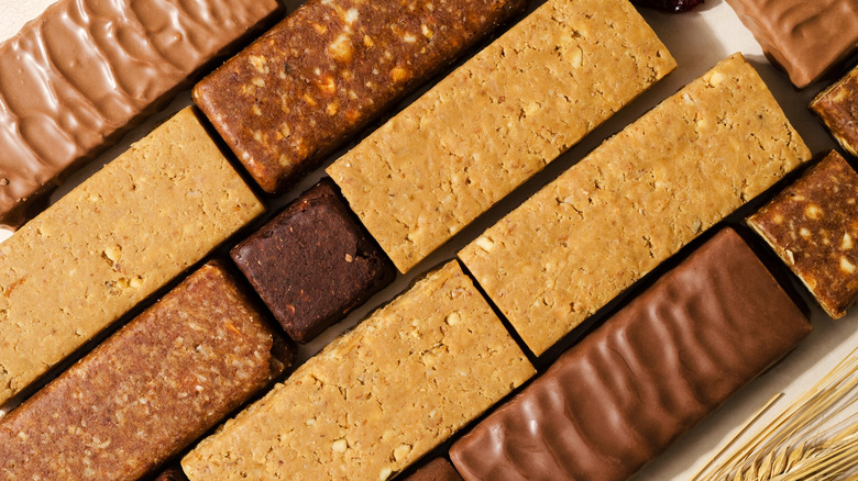 Assorted unwrapped energy bars lined up on a table, some covered in chocolate