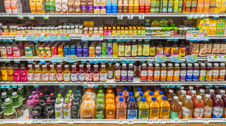 Several bottled smoothies, juices, probiotic drinks, and kombuchas in grocery store refrigerated aisle
