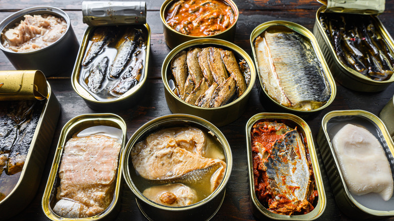 A variety of tinned fish, open to display contents, on a wooden tabletop