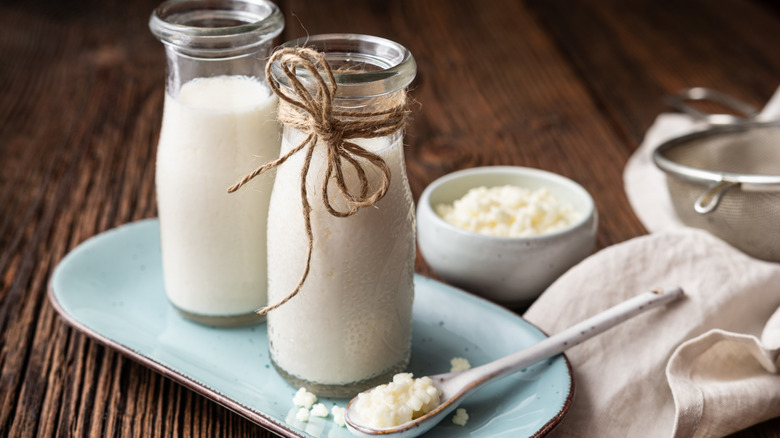 kefir in glass bottles with spoon on blue plate