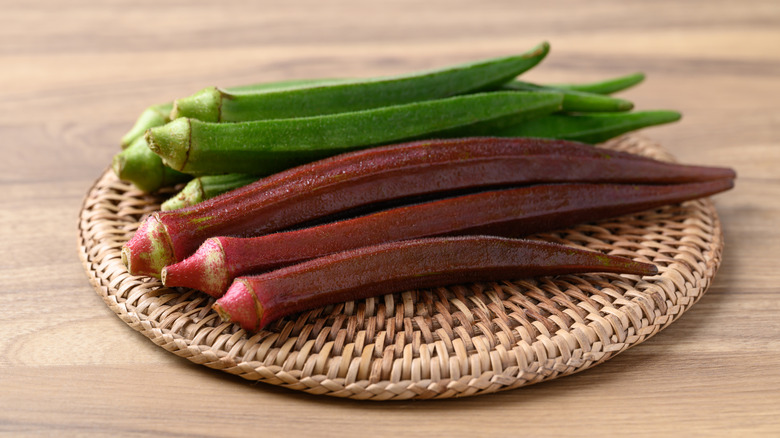 Green and red okra on wicker disc