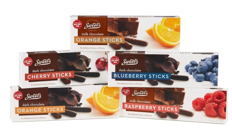 Boxes of Sweet's chocolate sticks in orange, cherry, blueberry, and raspberry flavors stacked against a white background