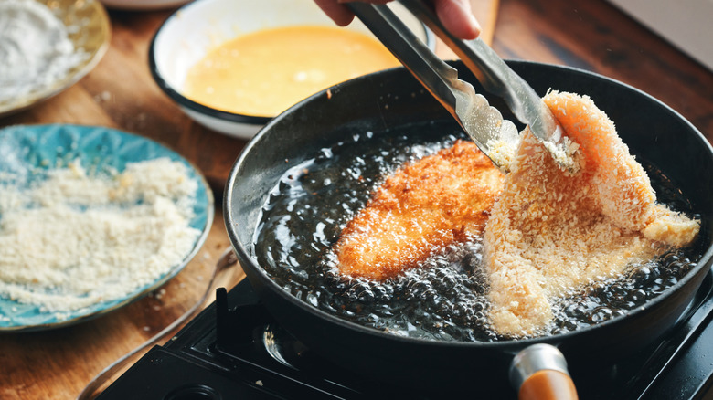Chicken pieces coated in panko breadcrumbs frying in a pan of oil