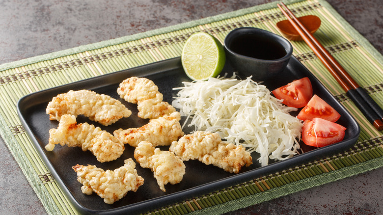 Toriten or chicken tempura pieces with vegetables on a black rectangular plate