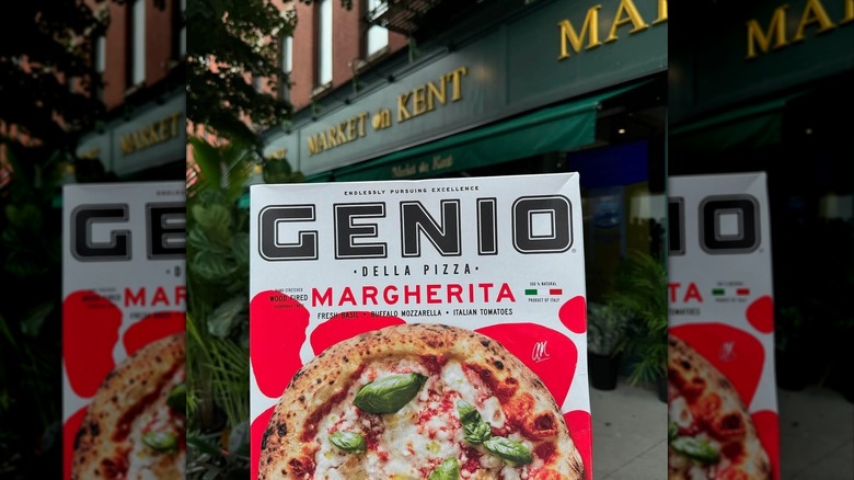 Someone holding up a Genio Della Pizza frozen pizza outside, mirrored