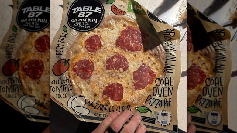 A hand over a Table 87 frozen pizza
