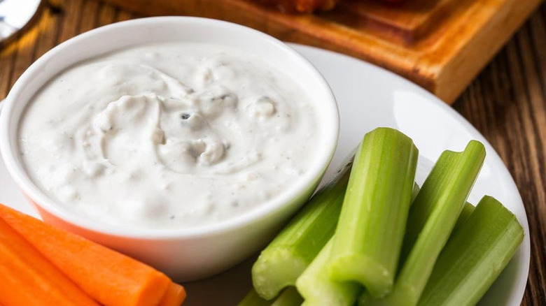 bowl of dressing with carrots and celery on the side