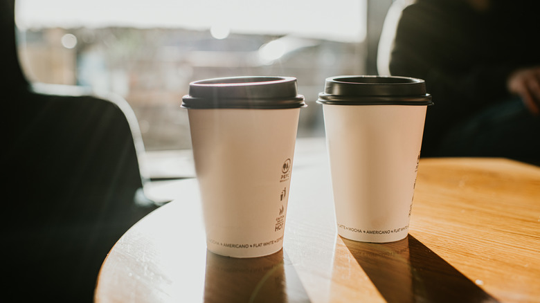 Two cups of to-go coffee on a table.