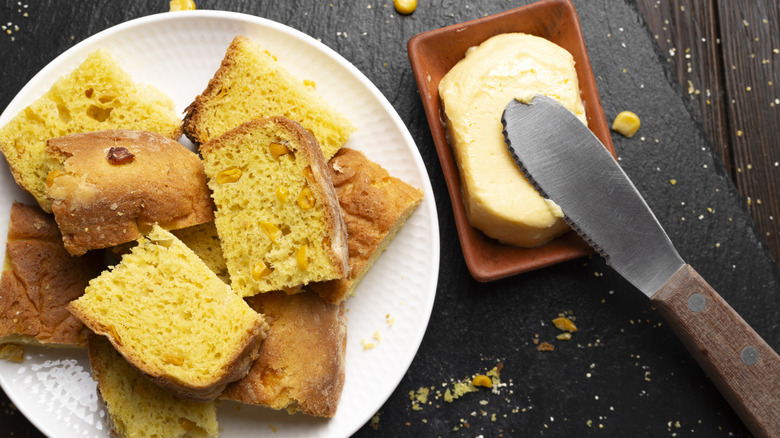 Cornbread slices on a white plate and a dish of butter