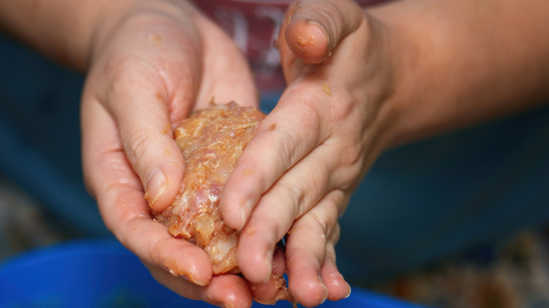 Woman's hands shaping ground meat with onion into a patty.