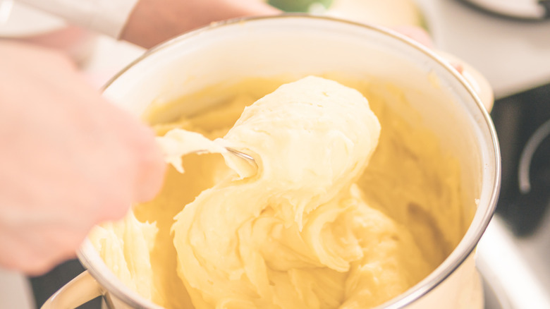 stirring mashed potatoes in a saucepan