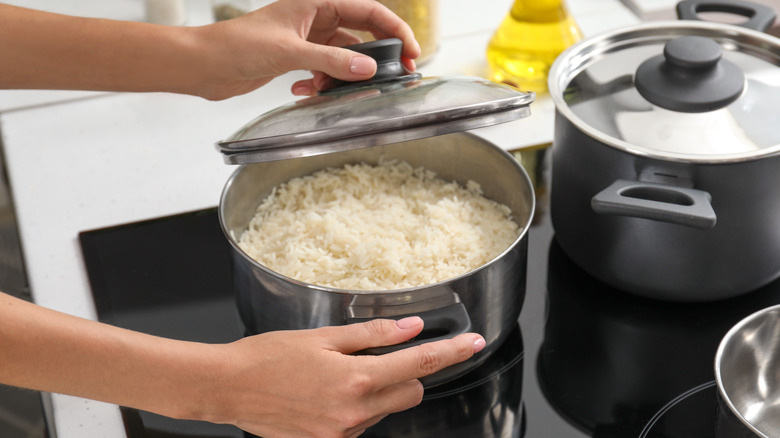 Woman cooking rice on stove in kitchen