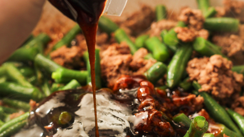 Pouring sweet soy glaze onto cooking beef and green beans