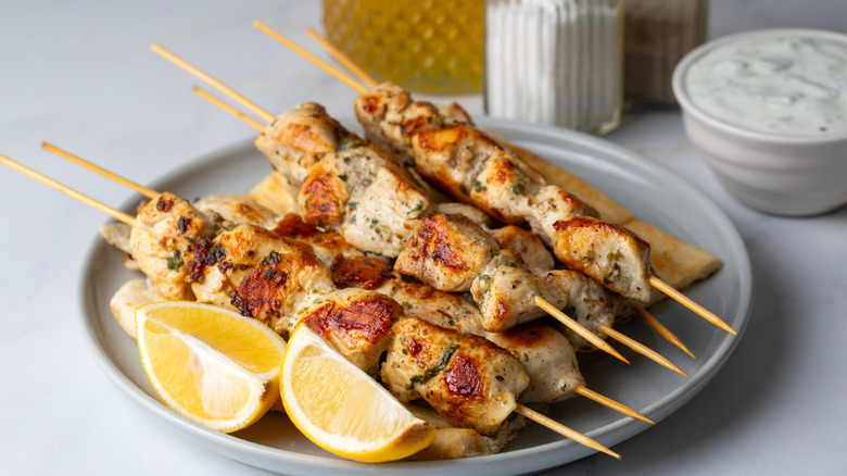 Greek grilled chicken skewers. Chicken souvlaki served with lemon wedges on a platter