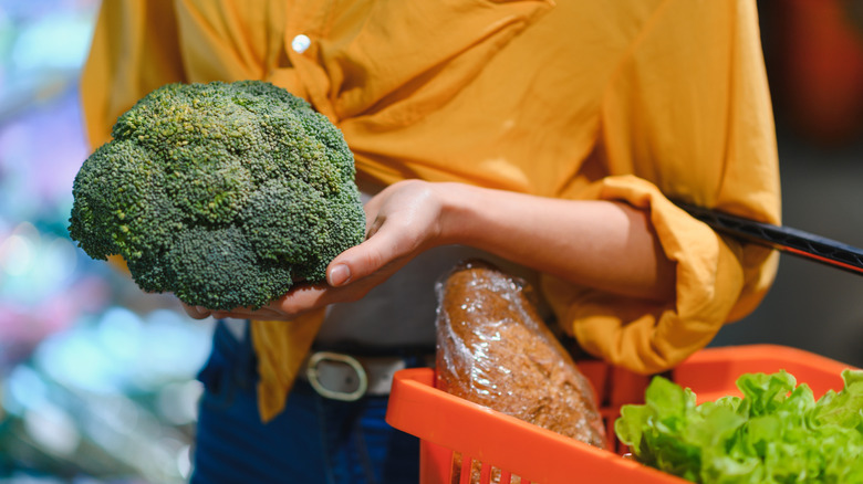 A woman shopping for broccoli in the supermarket