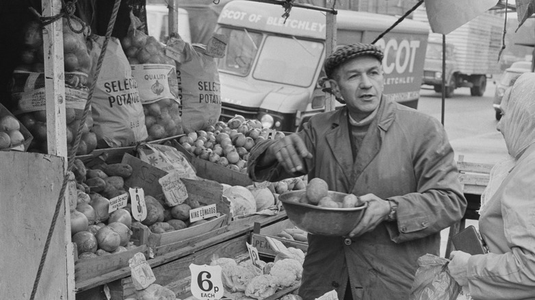 A street vendor selling potatoes, black and white