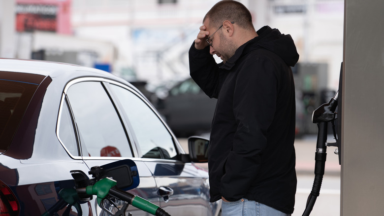 Frustrated man pumping gas into his car