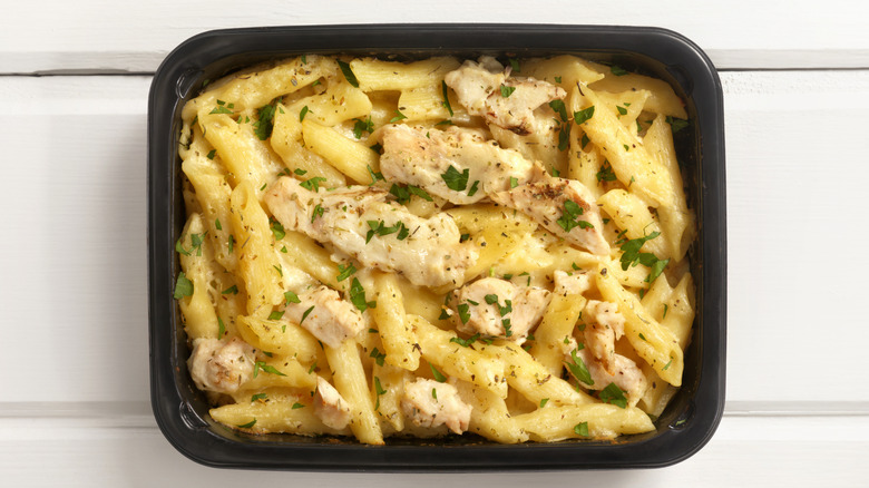 A cooked frozen dinner of penne pasta and chicken in cream sauce with herb garnish
