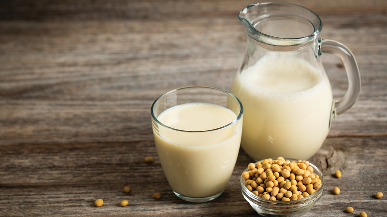 Soy milk in a glass and soybeans on the wooden table.