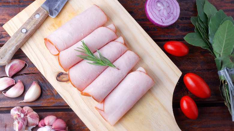 sliced cold smoked turkey breast over rustic wooden table. top view