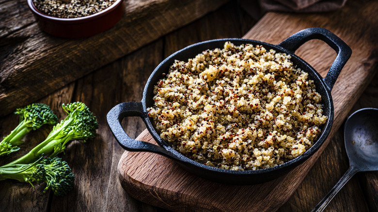 cooked quinoa in a cast iron pan shot on rustic wooden table.