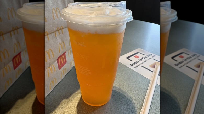 McDonald's Orange Dream Crafted Soda sitting on a dining room table near a bag of food.