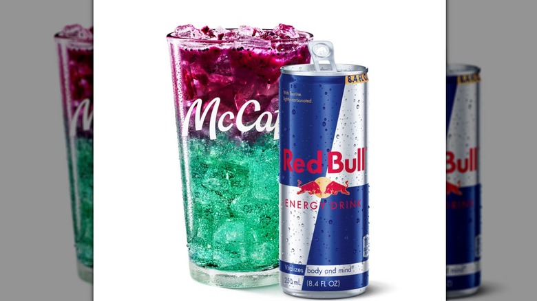 McDonald's Red Bull Dragonberry Energizer sitting in a glass next to a Red Bull can on a white background.