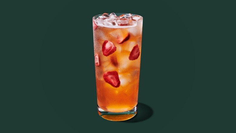 Starbucks Mango Strawberry Energy Refresher in a glass on a forest green background.
