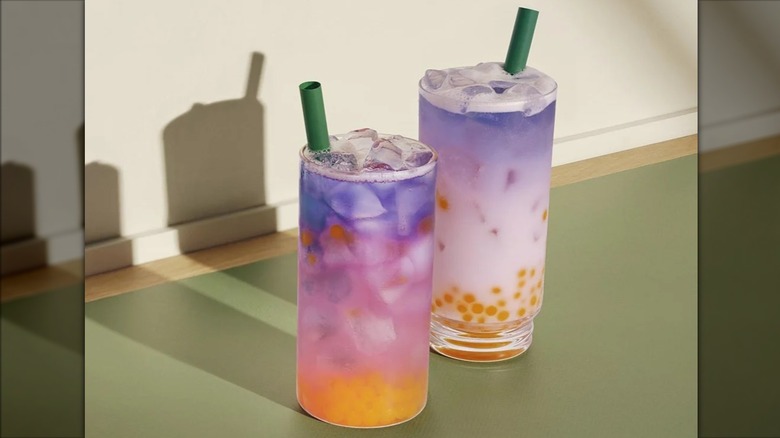 Two Starbucks Tropical Butterfly Refreshers on a pastel surface.
