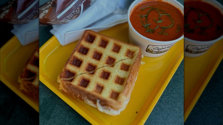 A Grilled Cheese Waffle sandwich with tomato soup on tray