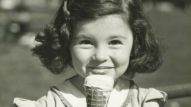 A girl in a black-and-white photo eating ice cream
