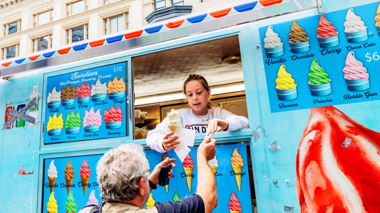 A woman giving a young customer ice cream from an ice cream truck